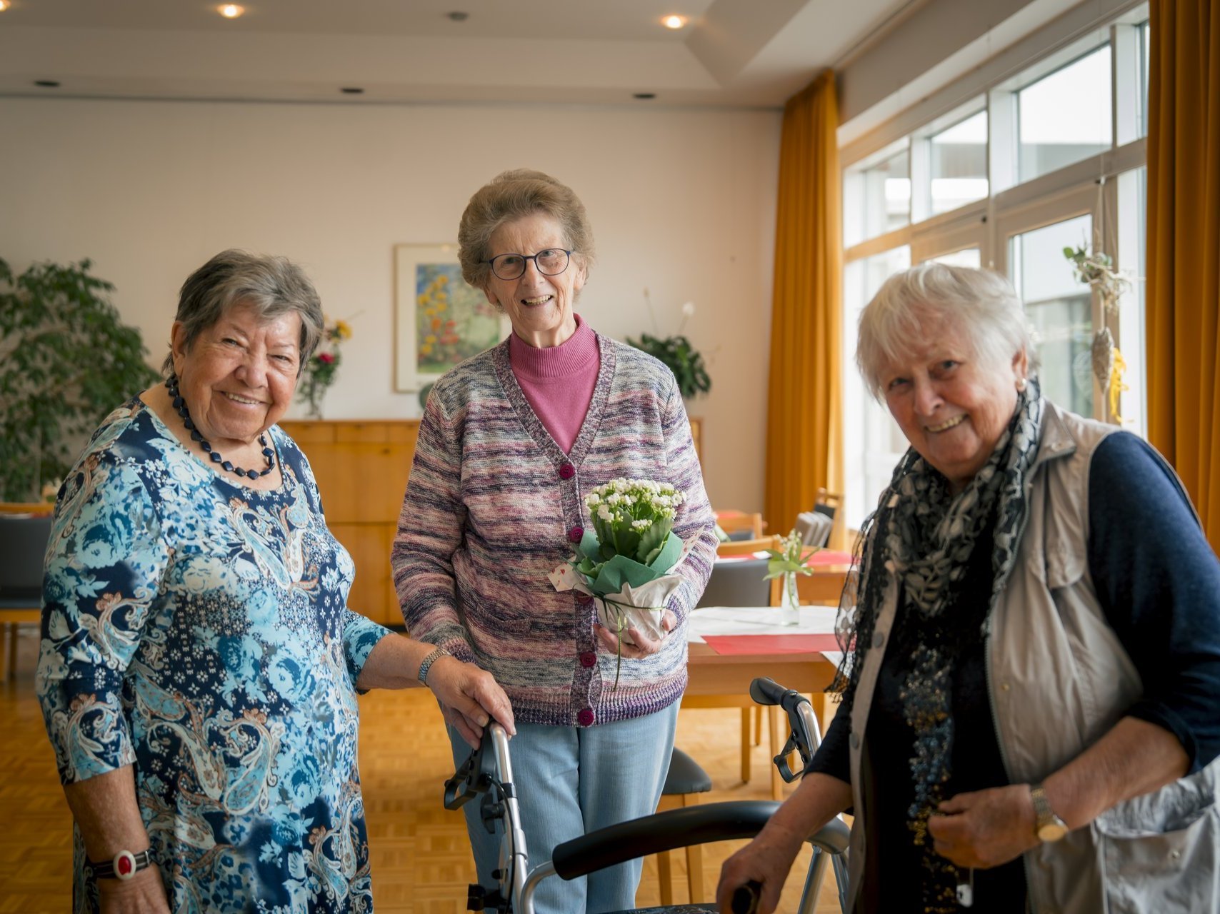 Drei Seniorinnen lächeln in die Kamera.