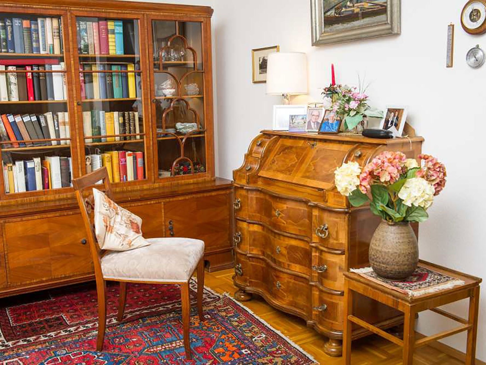 Edel eingerichtetes Zimmer mit Sekretär, Holzvitrine mit vielen Büchern und Geschirr